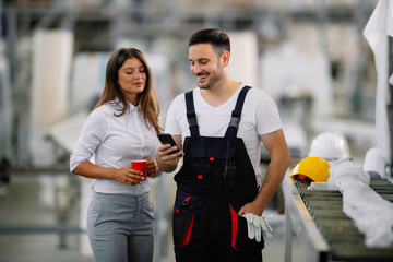 Colleagues on coffee break in factory. Architect and worker talking while drinking coffee together. 
