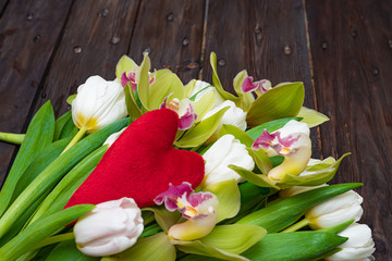 White tulips and green orchids on a dark wooden background. Concept of love.