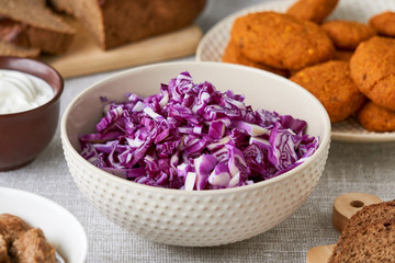 Red cabbage salad in a white bowl on a gray background