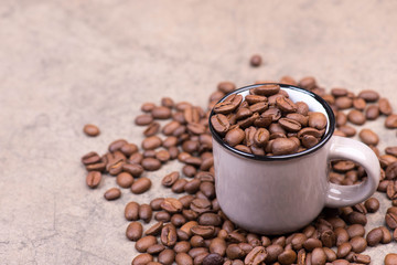 Roasted coffee beans on a brown textured stone background, empty copy space for text