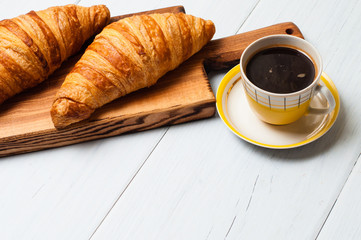Croissants and coffee on a light background. The concept of delicious breakfast or lunch. At the bottom there is a place for copy space