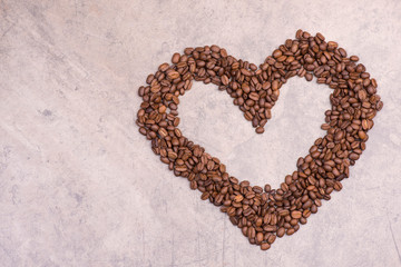 Coffee beans in the shape of a heart on a brown textured background