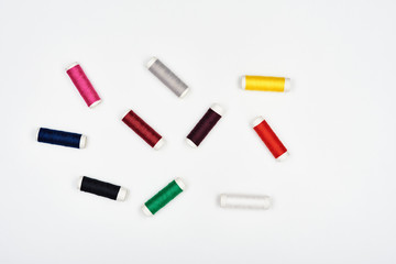 Spools with multi-colored beautiful threads for sewing on a white surface. Top view.