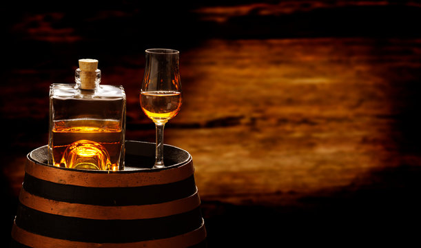 Whiskey bottle and whiskey glass stand on a whiskey barrel, whiskey drink in the distillery