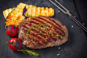 Juicy medium rare beef steak  on board with herbs spices and salt.