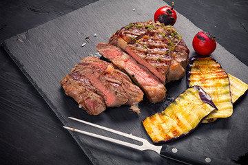 Juicy medium rare beef steak  on board with herbs spices and salt.