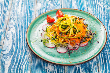 Vegetable pasta from carrot and zucchini. Served on a ceramic plate.