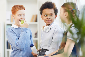 Group of school children eating and talking to each other during a break at school