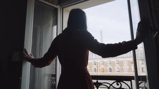 Young happy traveler woman opening balcony window, enjoying romantic sunny morning Paris Eiffel Tower view slow motion.