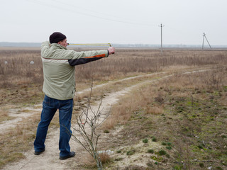 Young man shoots a slingshot in nature