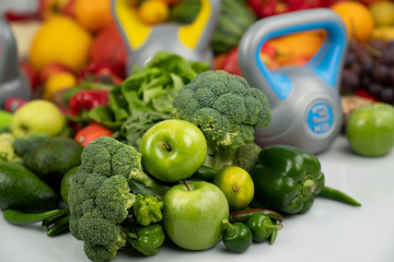 Fitness concept. Healthy nutrition: fruits and vegetables. Equipment for fitness exercises: weighing machine and dumbells. White background.