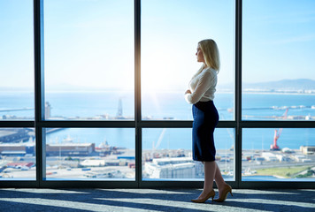 Young businesswoman looking at the city through office building windows