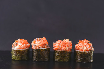 Set of four pieces of spicy Maki sushi rolls with sauced slices of smoked Eel, cheese and caviar of flying fish.