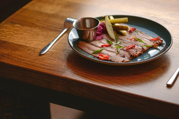 Carpaccio of beef with red cabagge and pickles served on blue plate on rustic wooden table in a...
