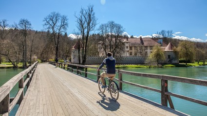 Male riding a bicycle near the Castle Otocec in Slovenia