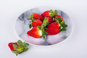 Delicious red strawberries on a marble plate. White background. Horizontal format