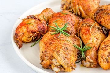 Close-Up Photo of Roast Chicken Pieces  with Rosemary on a Plate on White Background.