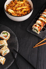 Traditional Asian cuisine sushi rolls and noodles on a black wooden table
