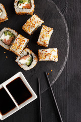 Traditional Asian cuisine sushi rolls and noodles on a black wooden table