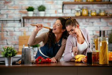 Two friends having fun in kitchen. Sisters cooking together.
