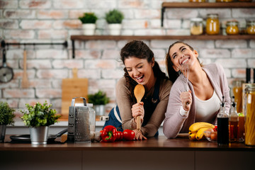 Two friends having fun in kitchen. Sisters cooking together.