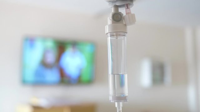 Close-up of Saline solution drip for patient and infusion pump on blurred luxury VIP room background in hospital.