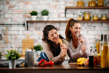 Two friends having fun in kitchen. Sisters cooking together.