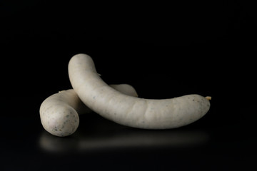 Two long white raw bratwurst sausage isolated on black background