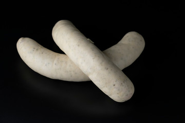 Two long white raw bratwurst sausage isolated on black background