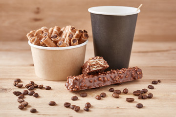 Paper coffee cups and chocolate sweets on wooden background