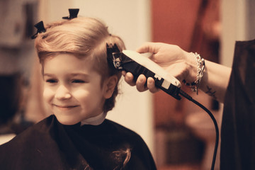 Cute kid during haircut at barber shop.