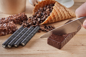 hand cut waffle with knife ,chocolate sweets on wooden background, top view