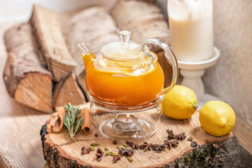Sea Buckthorn tea candle basking. Vitaminic healthy sea buckthorn tea with cinnamon sticks, lemon, rosemary, honey on wooden background.