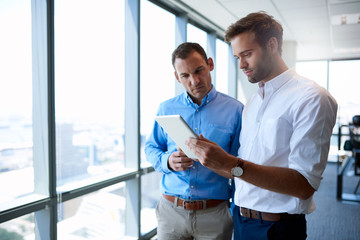 Business coworkers looking at digital tablet in modern office