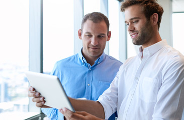 Young businessman showing colleague something on digital tablet