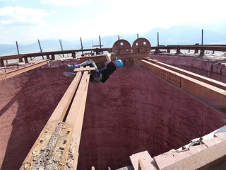 Athlete man hanging an iron rail on top of a tall industrial chimney with the risk of falling to...