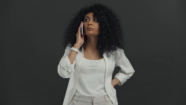 attentive bi-racial woman talking on smartphone isolated on black