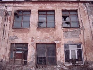 Fototapeta na wymiar Abandoned house. Broken down windows. Broken glass. Old paint on the brick walls.