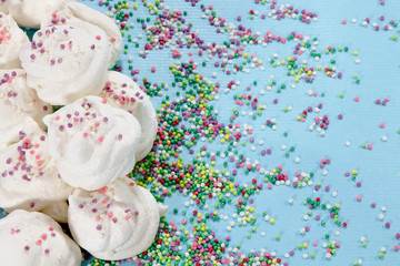 White marshmallows on a blue background. Confectionery for the holiday. Multicolored dragees in a...