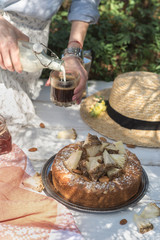 Girl on a picnic pours milk into a glass with coffee
