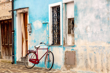 Fototapeta na wymiar Old blue house with a bicycle. Colorful houses in Burano island near Venice, Italy.