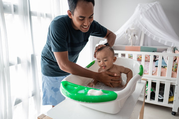 Obraz premium happy asian father taking bath of his baby toddler