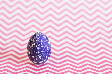 Blue Easter egg on a pink geometric background.