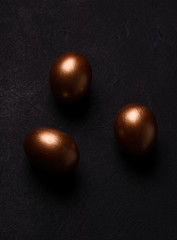 copper colored easter eggs on a black background. moody style