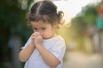 Cute asian little girl closed her eyes and praying in the morning. Little asian girl hand praying,Hands folded in prayer concept for faith,spirituality and religion.