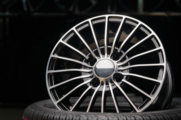 cast aluminum wheels in the store. thin spokes, beautiful black color and dark background. the wheels are on the tire.