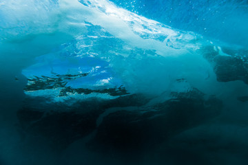 Wave with bubbles underwater. Transparent blue ocean in underwater