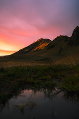 Fototapeta na wymiar Beautiful scenic sunset in Iceland. Yellow lit mountain side with pink clouds.wate