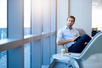 Young businessman in corporate space with sunflare through large windows