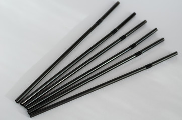 Six tubules for cocktails on a light background. Black drinking straws on the table. Close-up....